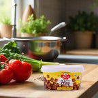 Container of Premium Hing Cubes – Strong Aroma & Authentic Indian Flavor on a kitchen counter with vegetables and cooking utensils in the background